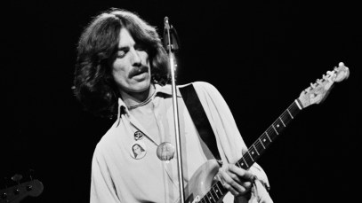 George Harrison plays the guitar on stage in 1974.