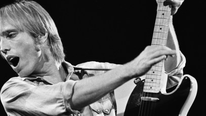 Tom Petty performing live with his guitar held high.