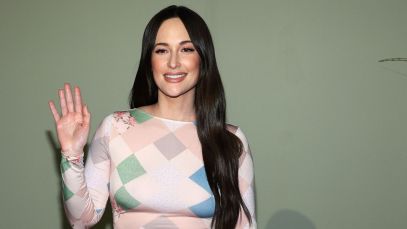 Kacey Musgraves waves in a pink multi-patterned dress.
