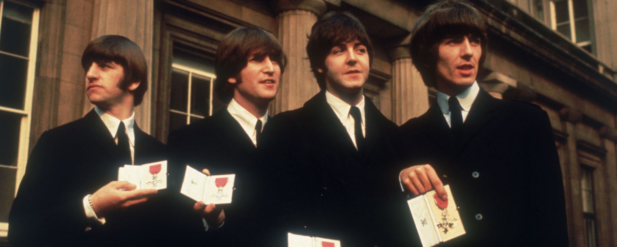The Beatles standing together holding medals