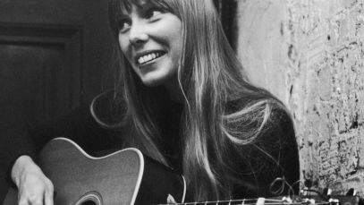 Joni Mitchell smiling, playing guitar