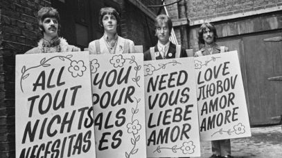 The Beatles posing with sandwich signs that say "All you need is love" in different languages