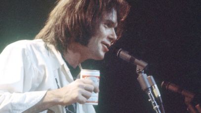 Neil Young performing, holding beer