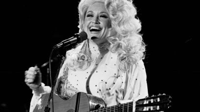 Dolly Parton smiling with guitar